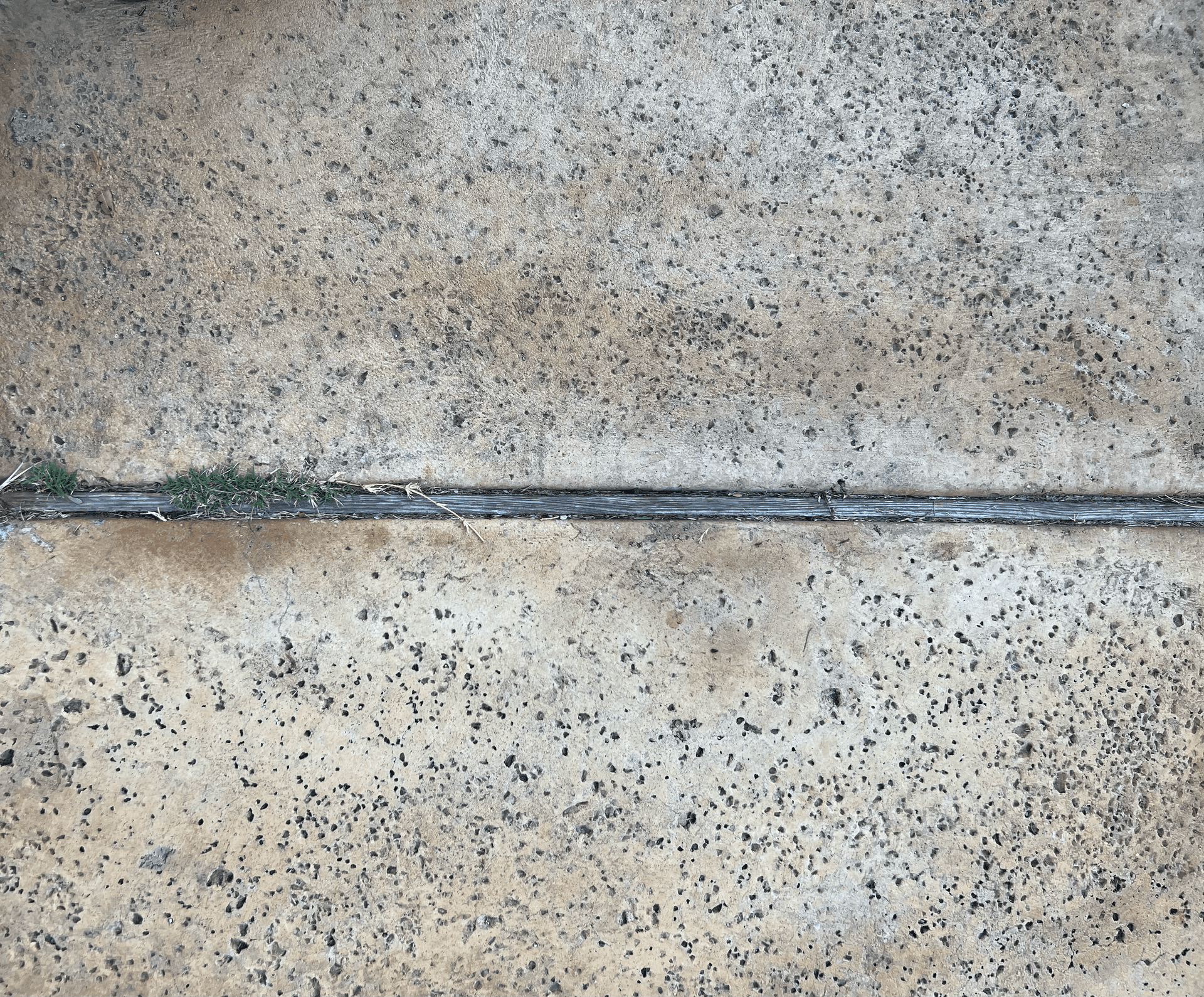 Replacing rotted wood expansion joint with polymeric sand in concrete driveway, Austin TX